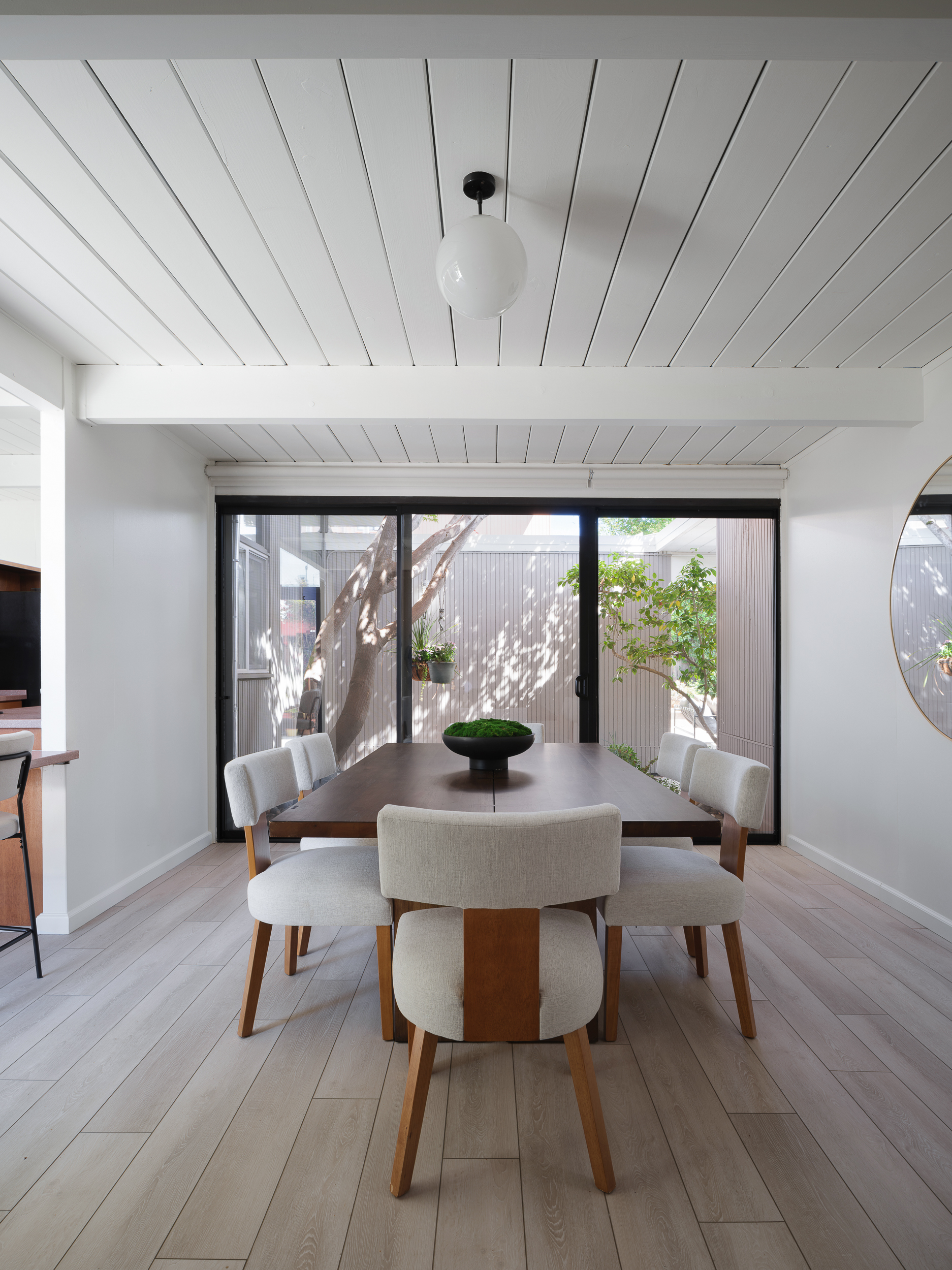 Dark wood dining table with cream chairs in bright room showing daily dining proportion
