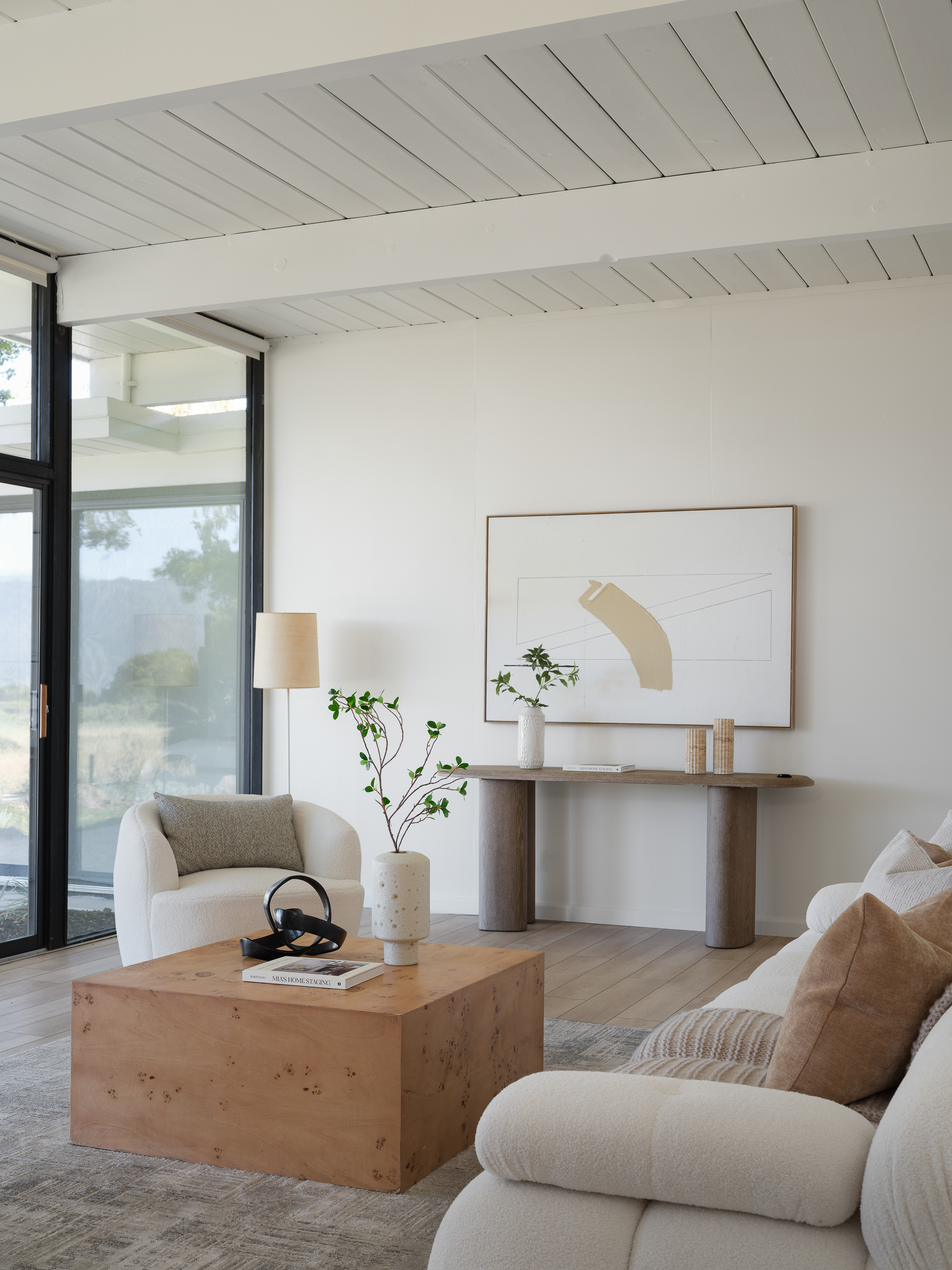 Wide living room with cream bouclé seating and tall glass showing scale without clutter