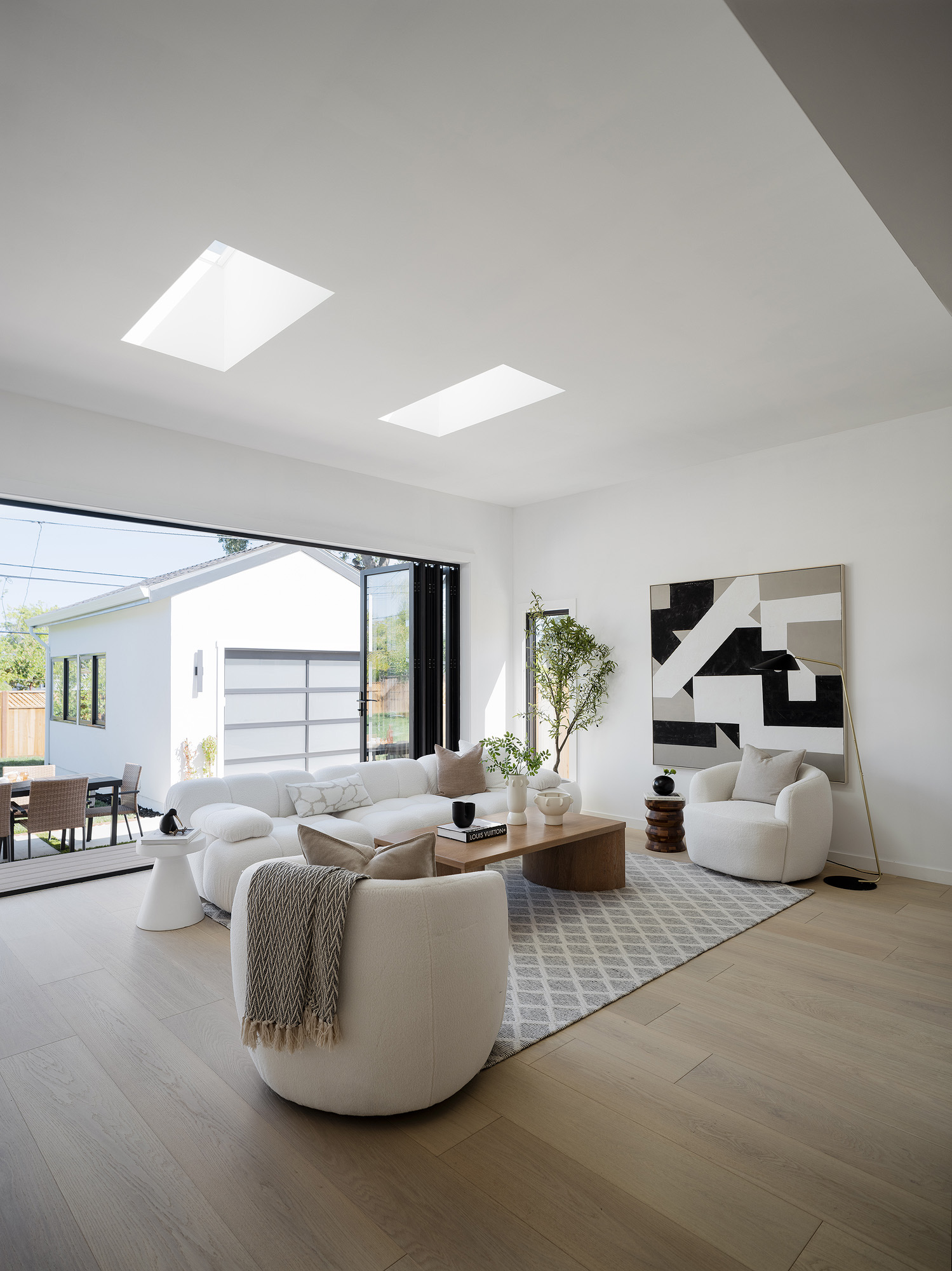 Bright modern living room with cream boucle seating, skylights, and open floor space for cool July showings