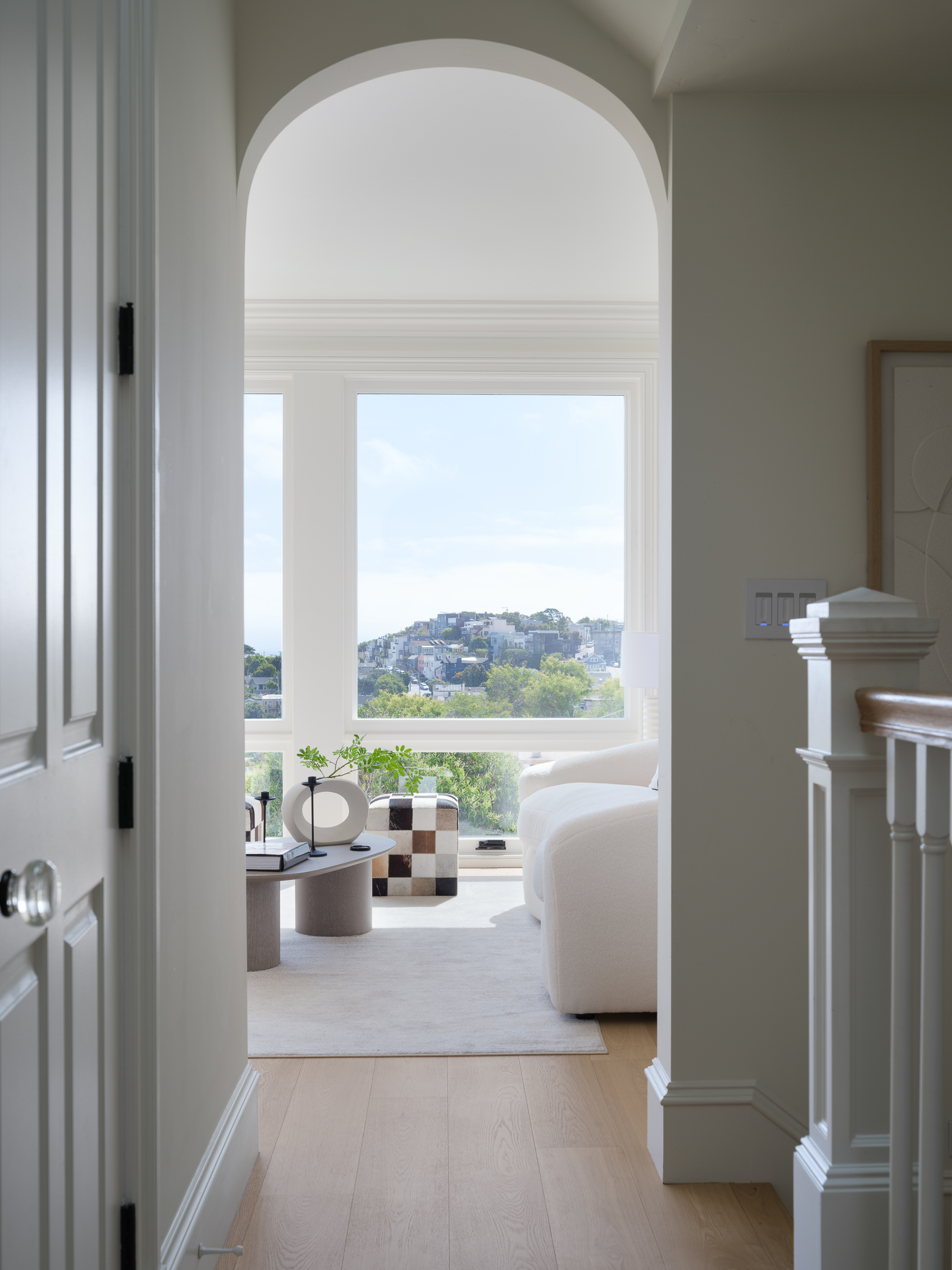 Arched doorway opening to a bright staged living room, showing first-impression scale and flow