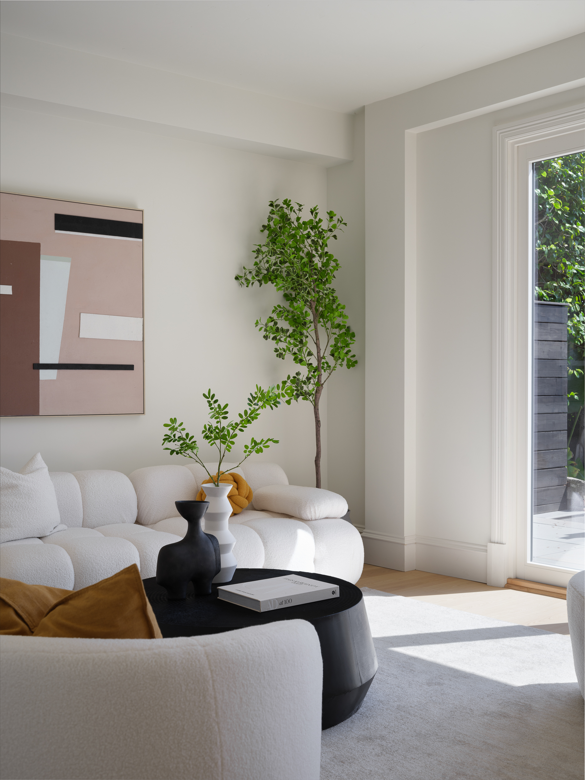 Cream bouclé sectional with black drum coffee table, garden light, and edited textures