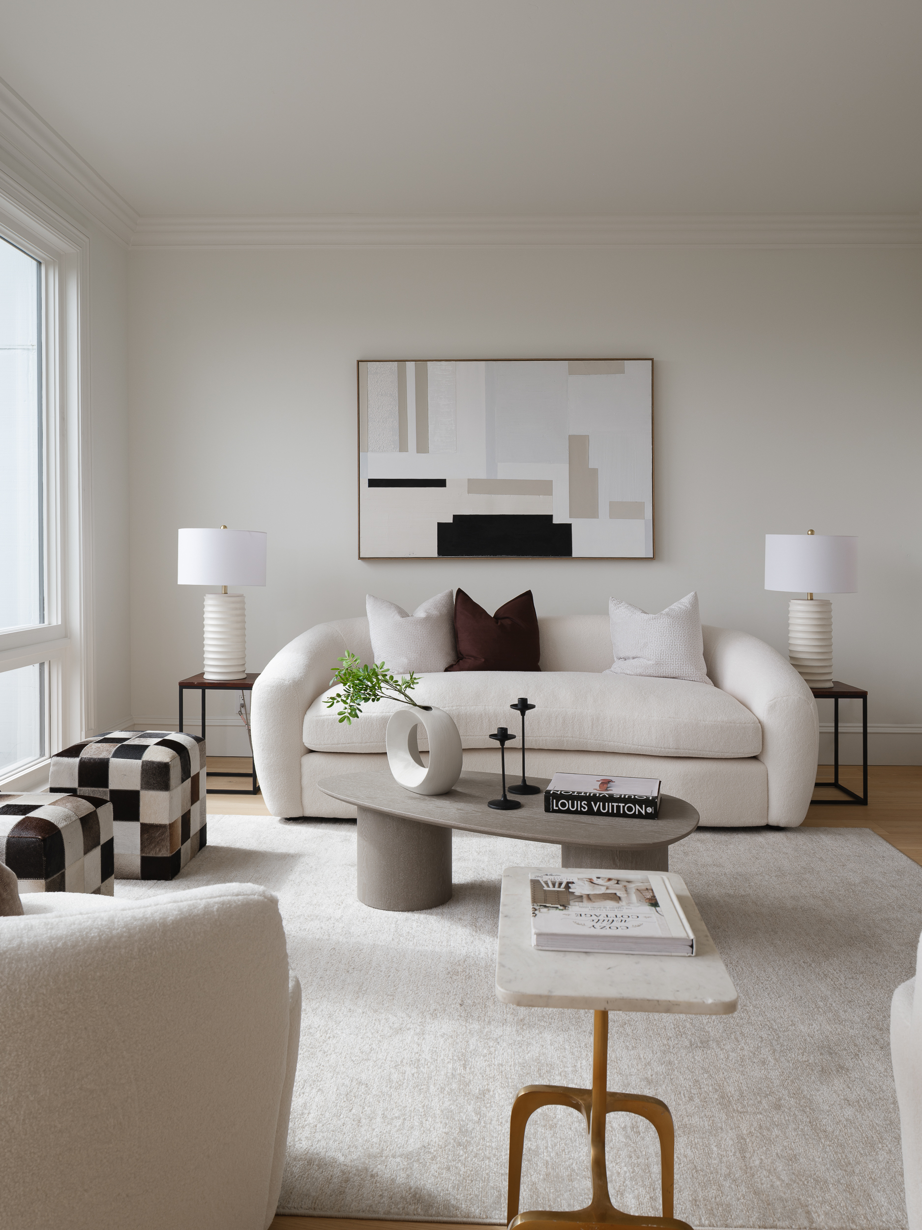 Cream curved sofa, abstract art, and warm wood accents showing restrained living room staging