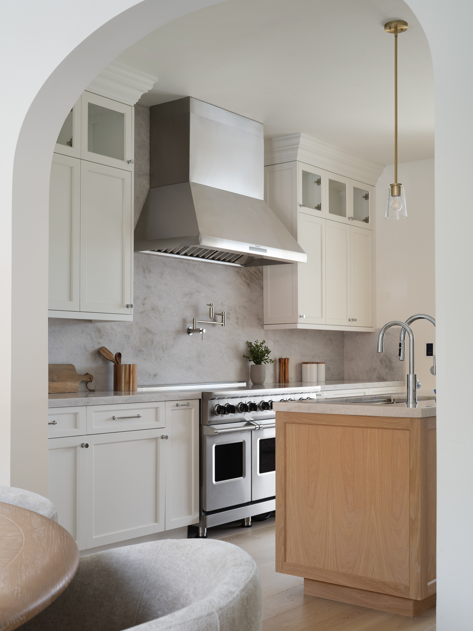 Bright kitchen with cream cabinetry, stainless range hood, and marble-look backsplash for clear selling prep