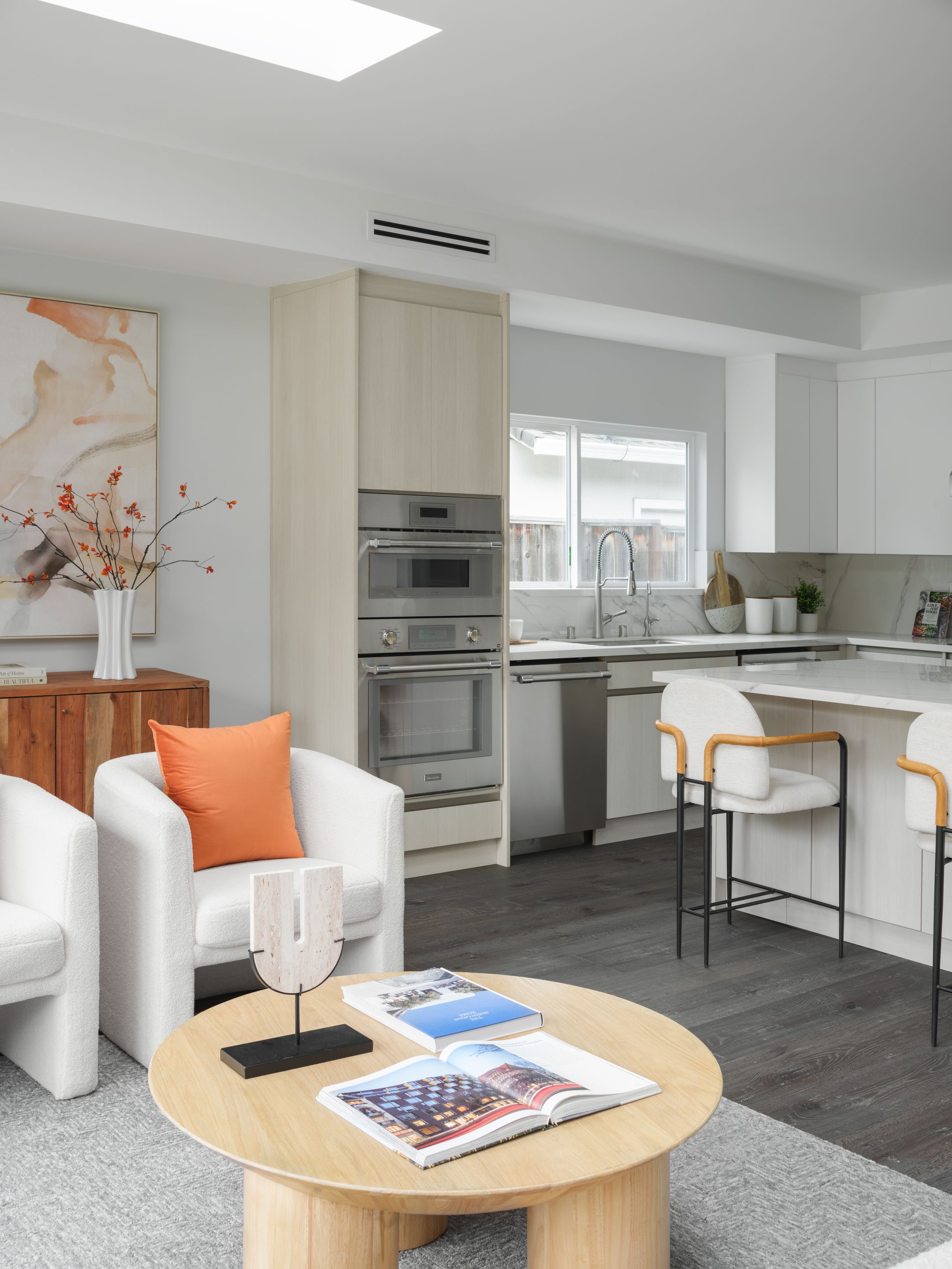 Pale oak kitchen and sitting area with white bouclé chairs and terracotta accents for buyer-friendly warmth
