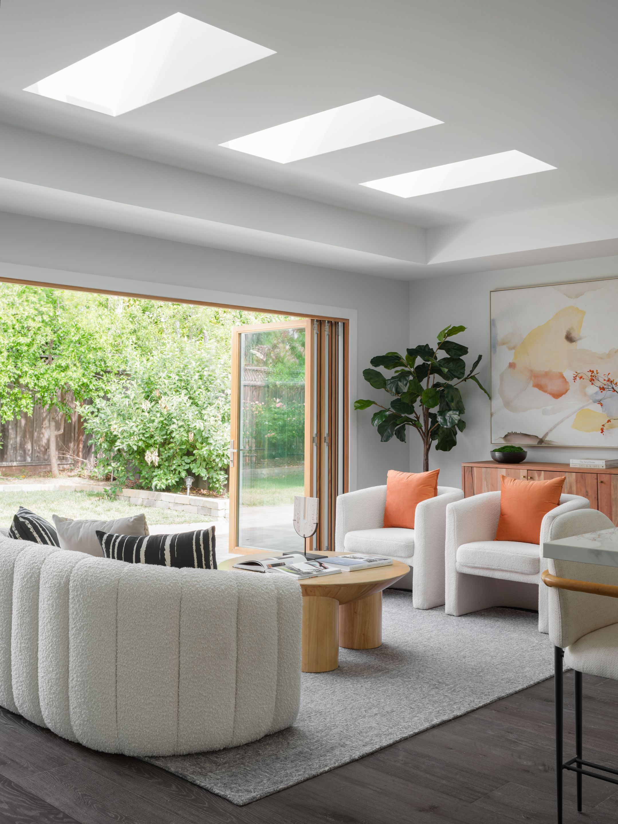 Bright living room with skylights, cream bouclé seating, and sliding doors holding calm on screen and in person