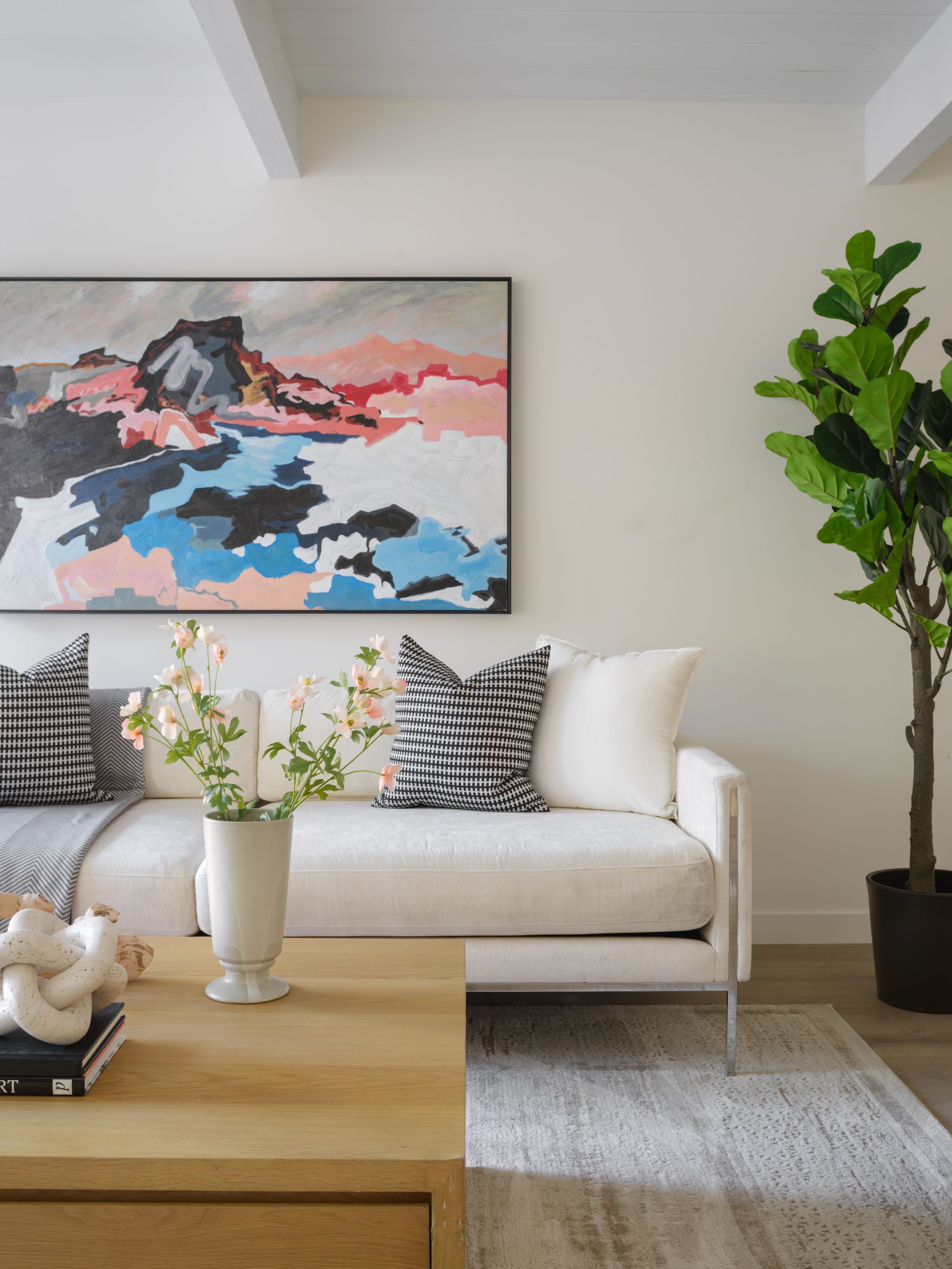Cream sofa, black-and-white pillows, light wood table, and abstract art demonstrating contrast within a warm neutral palette