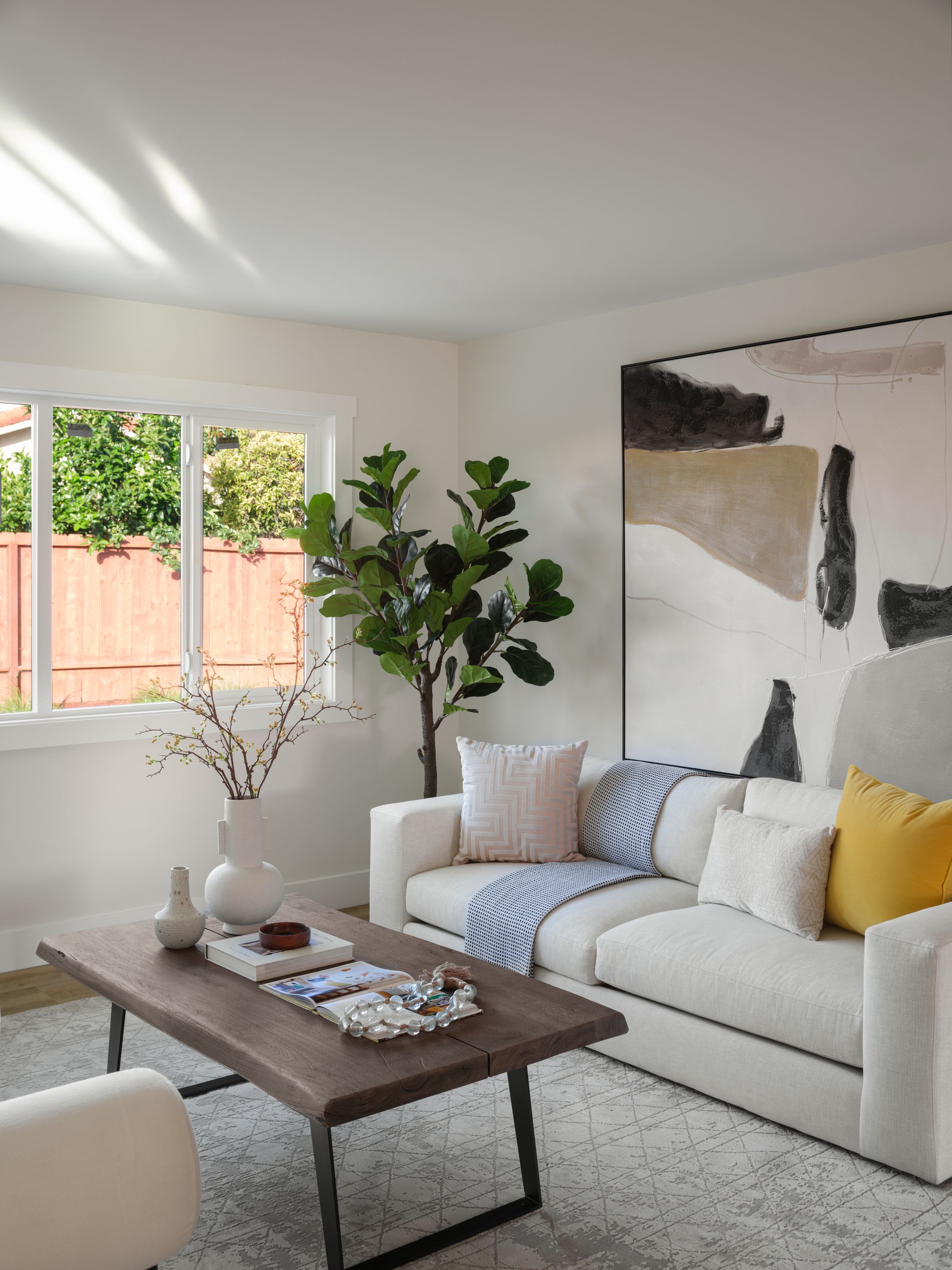 Sheer daylight fills a cream living room with garden-facing windows, showing filtered light for summer tours