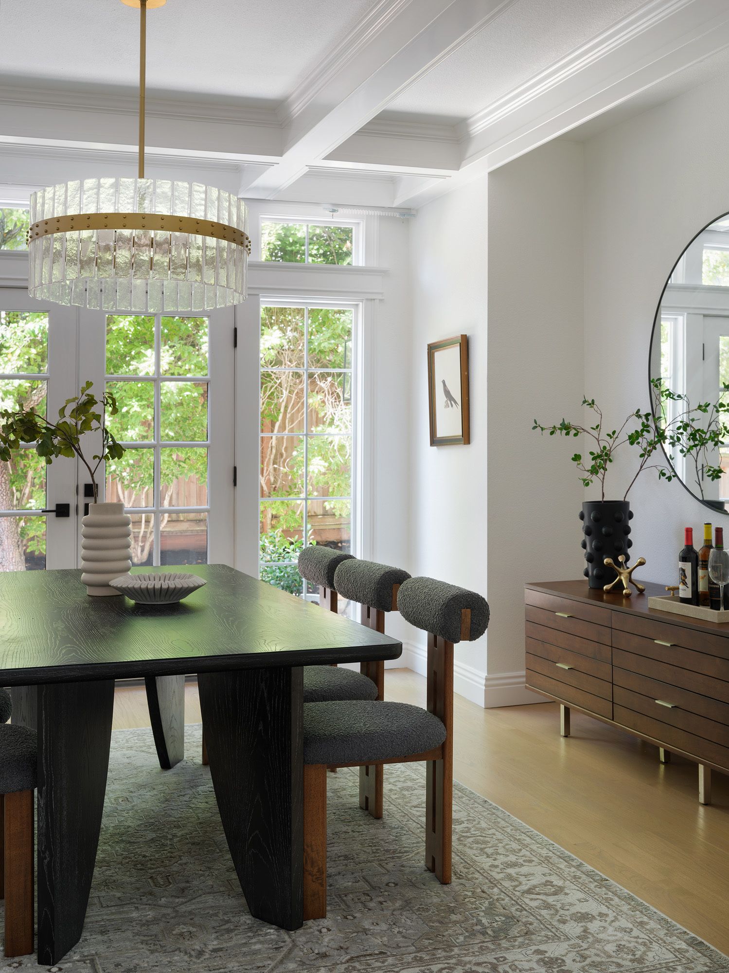 Muted patterned rug beneath a black dining table and gray upholstered chairs illustrates a restrained dining-room palette.