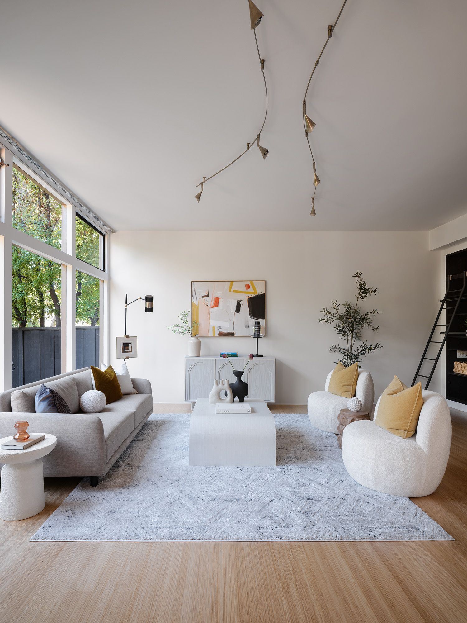 Large living room planned with a gray sofa, paired boucle chairs, coffee table, and tall windows