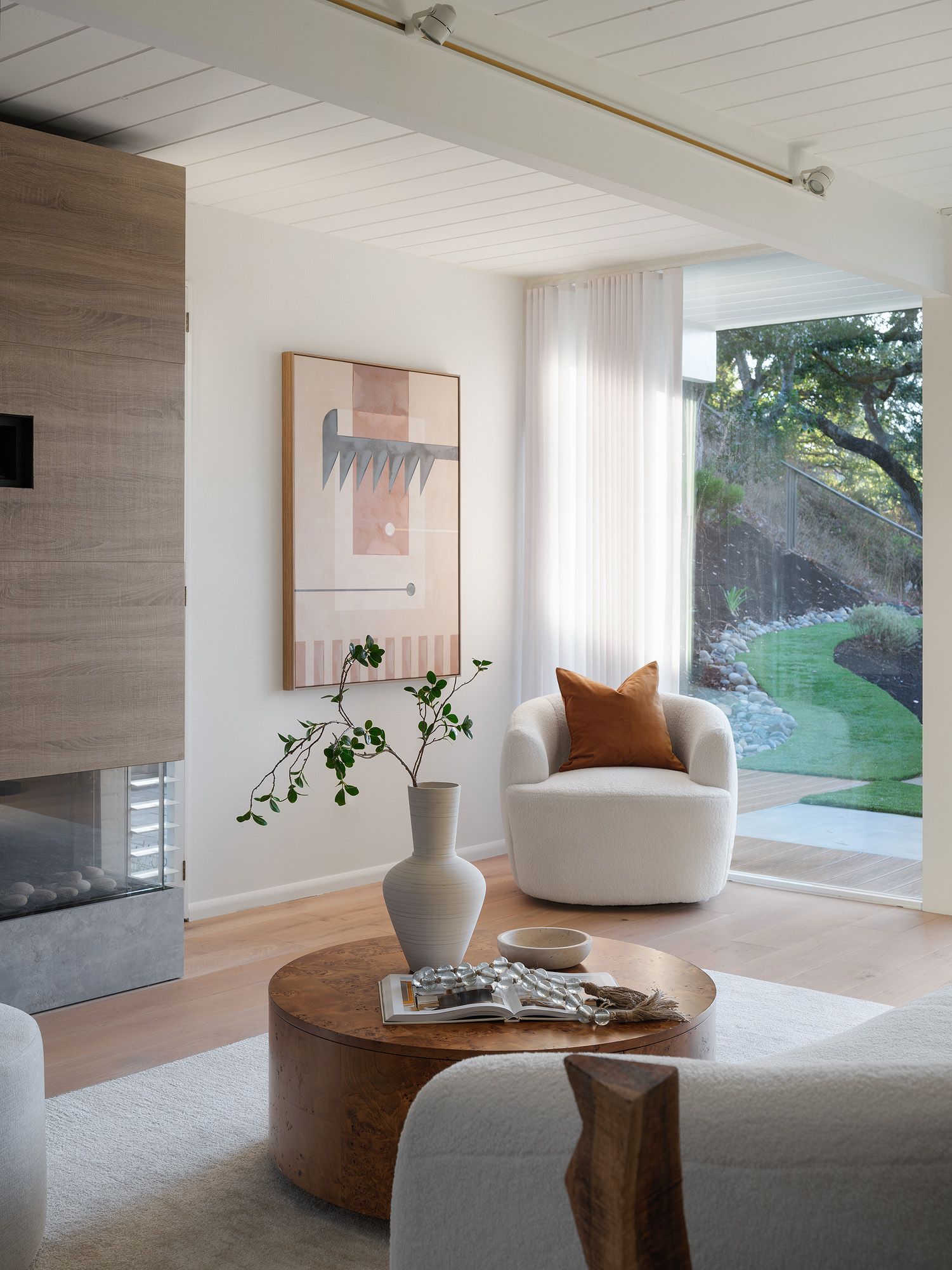 Cream boucle chair, burl wood table, ceramic vessel, and open book layer tactile texture in a neutral room