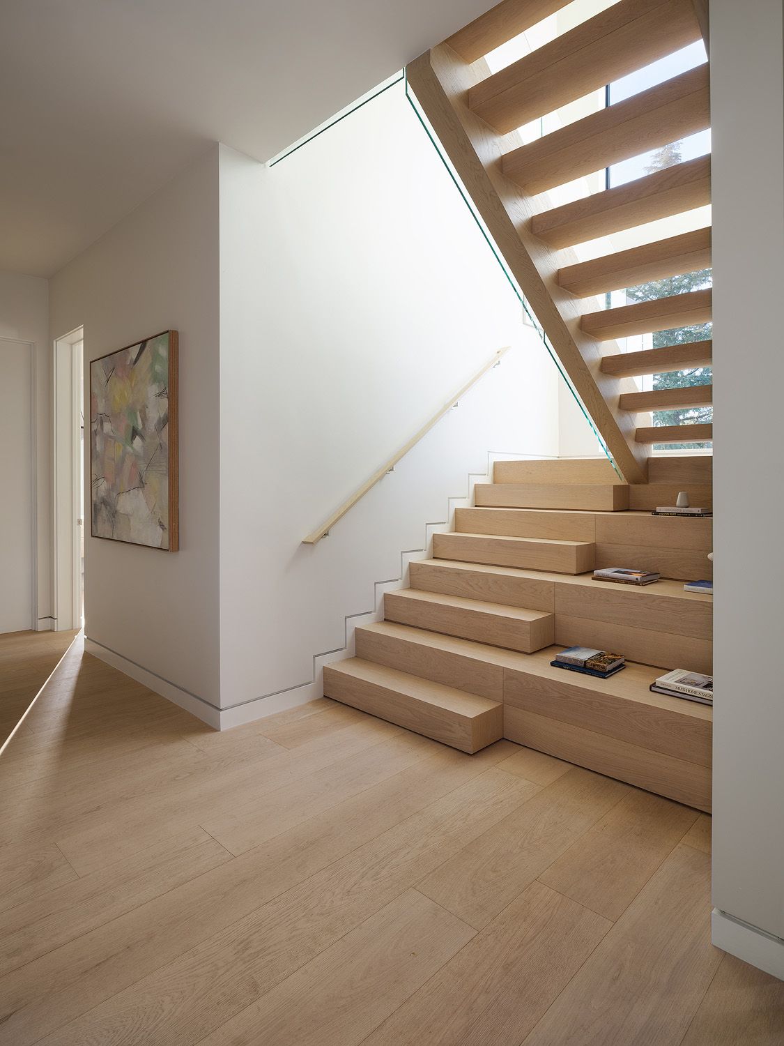 Oak staircase with glass railing and abstract wall art illustrates the access details to discuss before staging delivery.