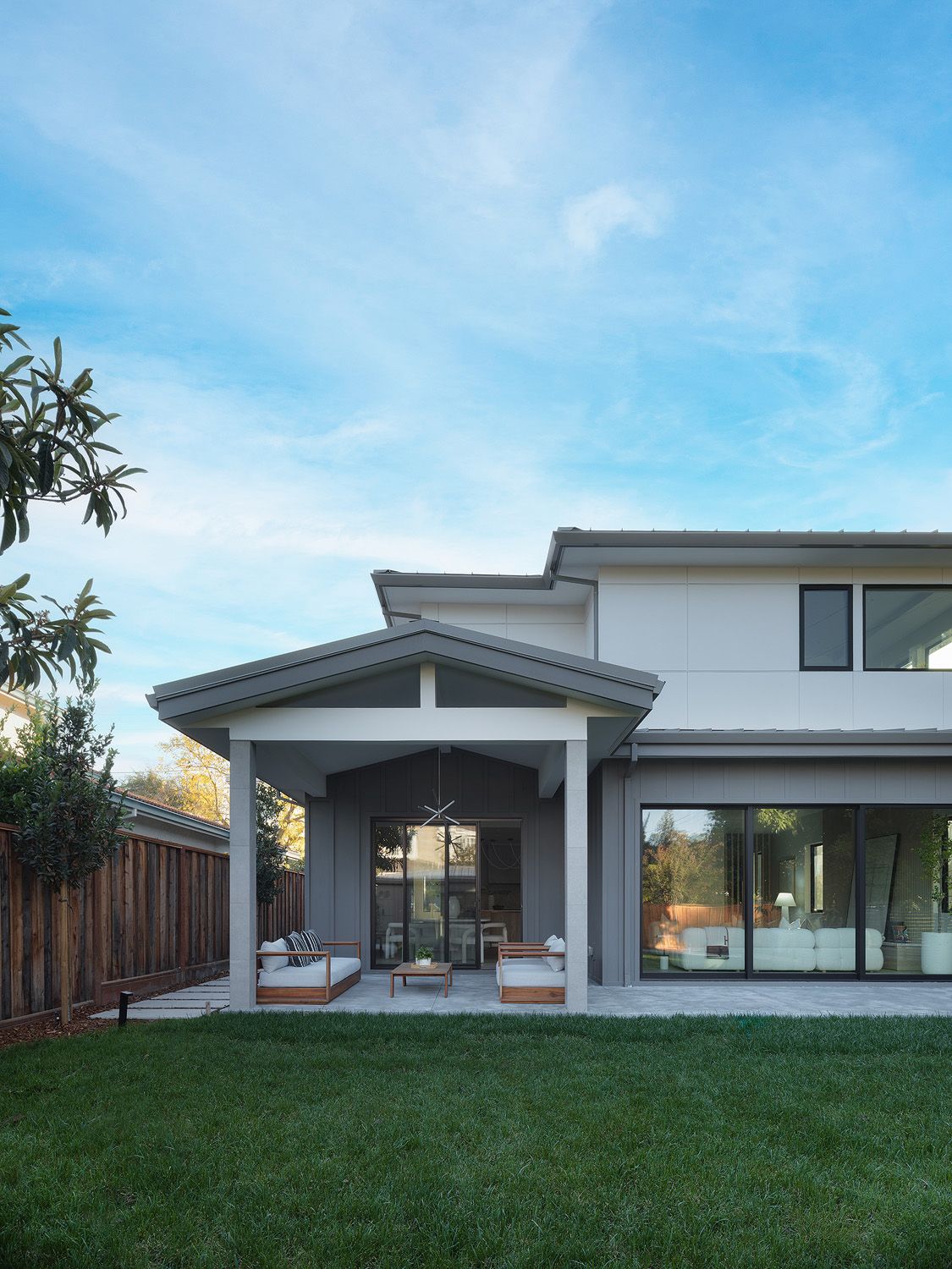 Covered backyard patio with wood seating, lawn, and glass doors making outdoor space feel usable