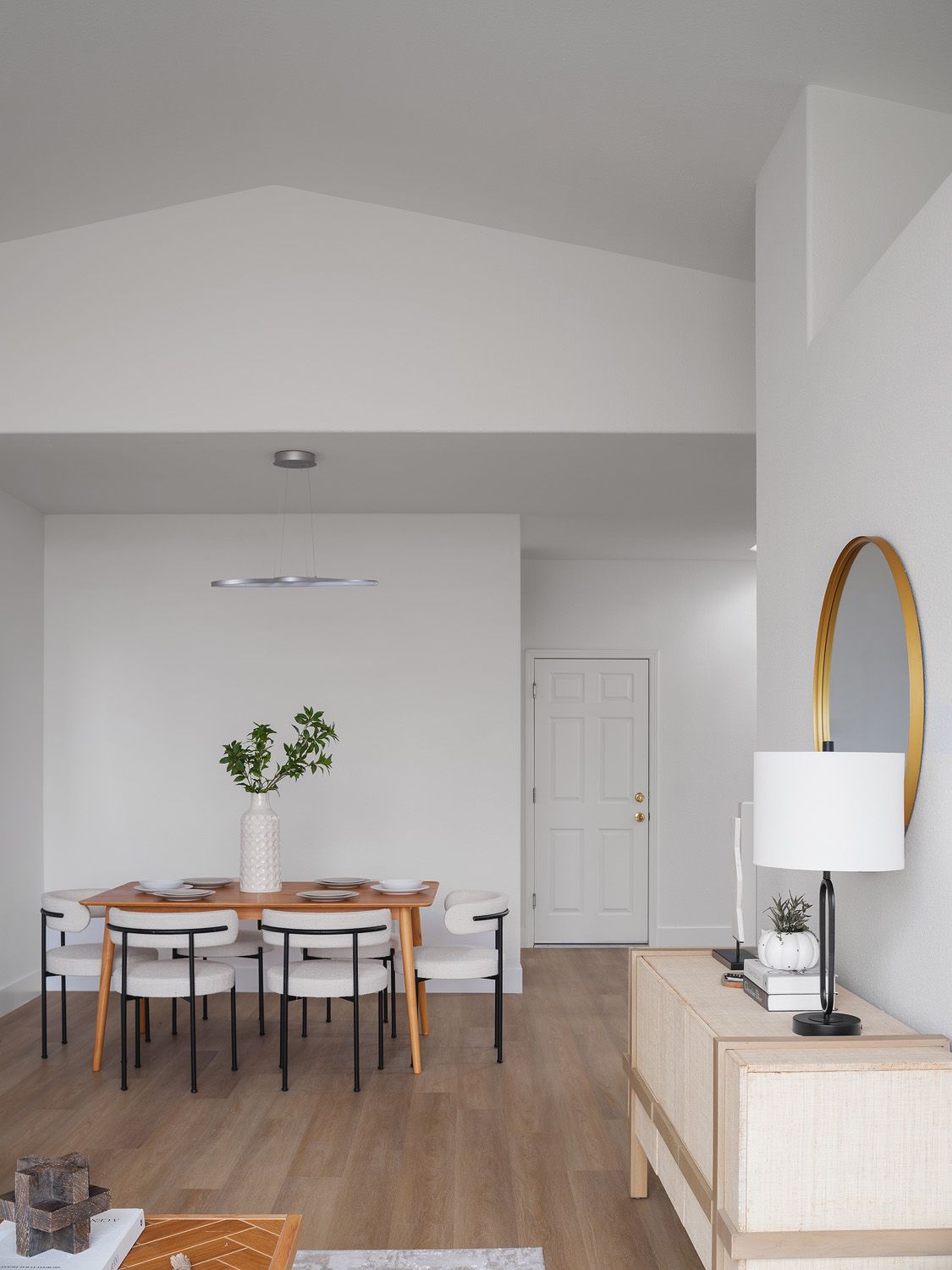 Slim natural wood dining table and light wood sideboard create warmth while keeping the open area airy