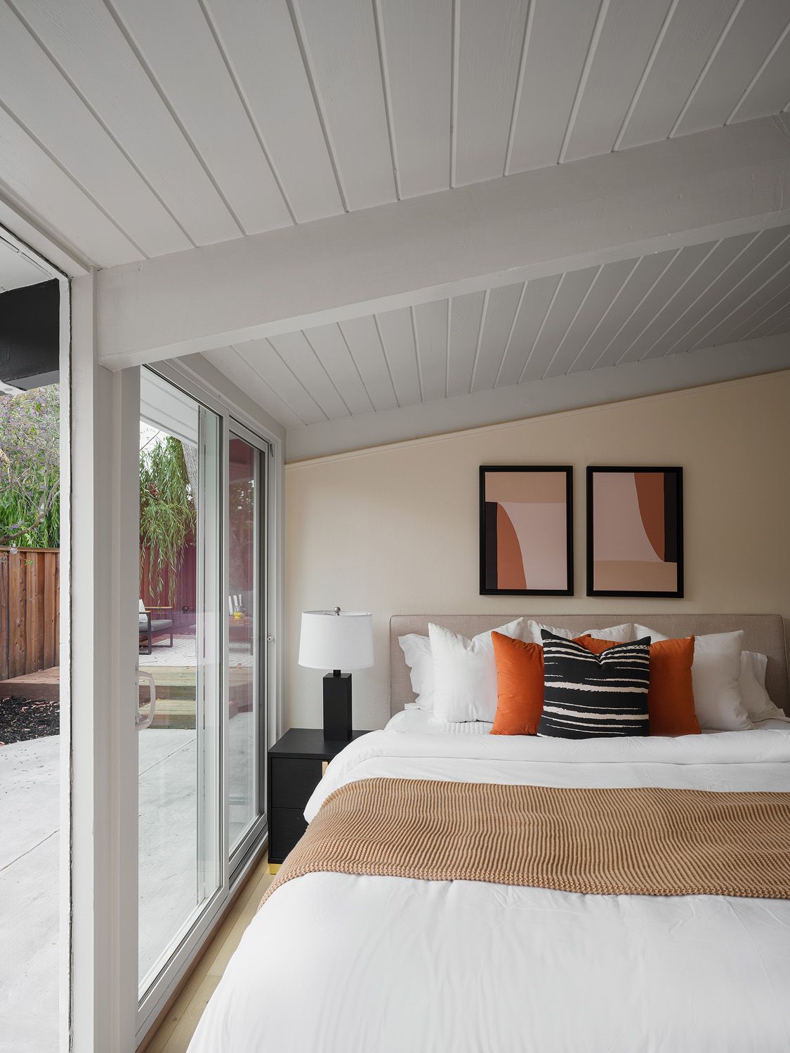 Warm modern bedroom with terracotta pillows and patio light for muted color in bedrooms