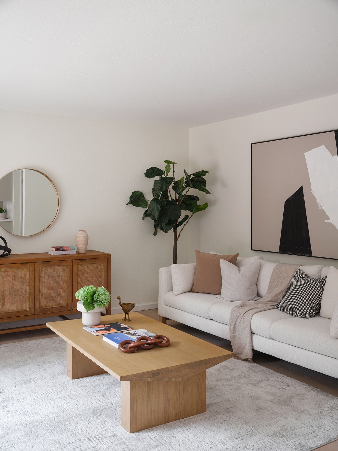 Neutral living room with cream sofa, cane credenza, oak table, and warm mineral tones