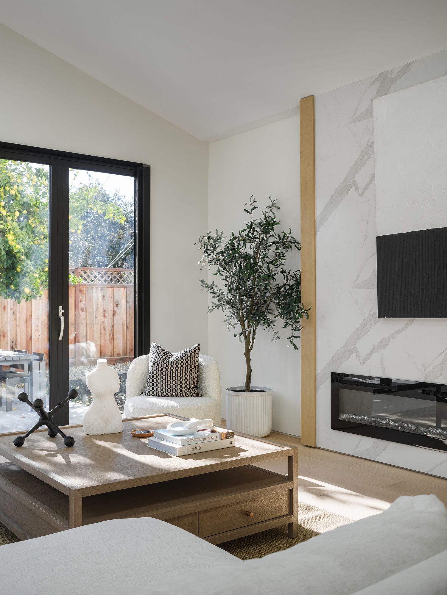 Light oak coffee table, woven chair, textured upholstery, and stone fireplace add natural depth to a neutral room