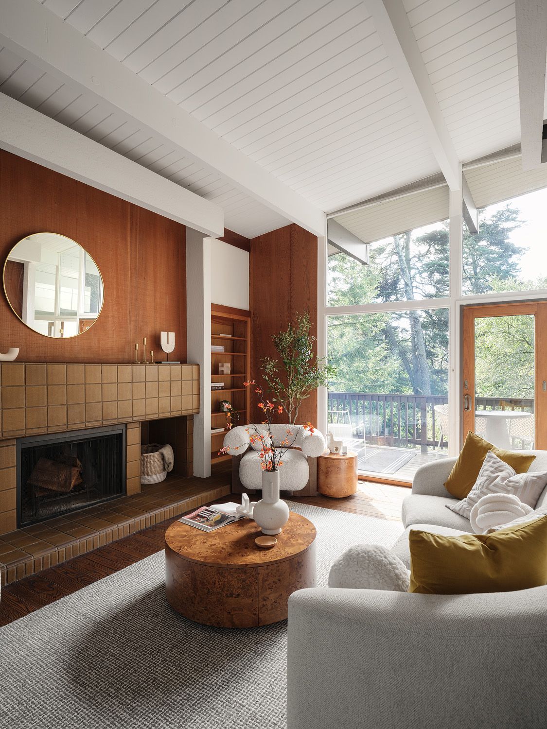 Mid-century living room with wood paneling, cream seating, and sunlight respecting the architecture