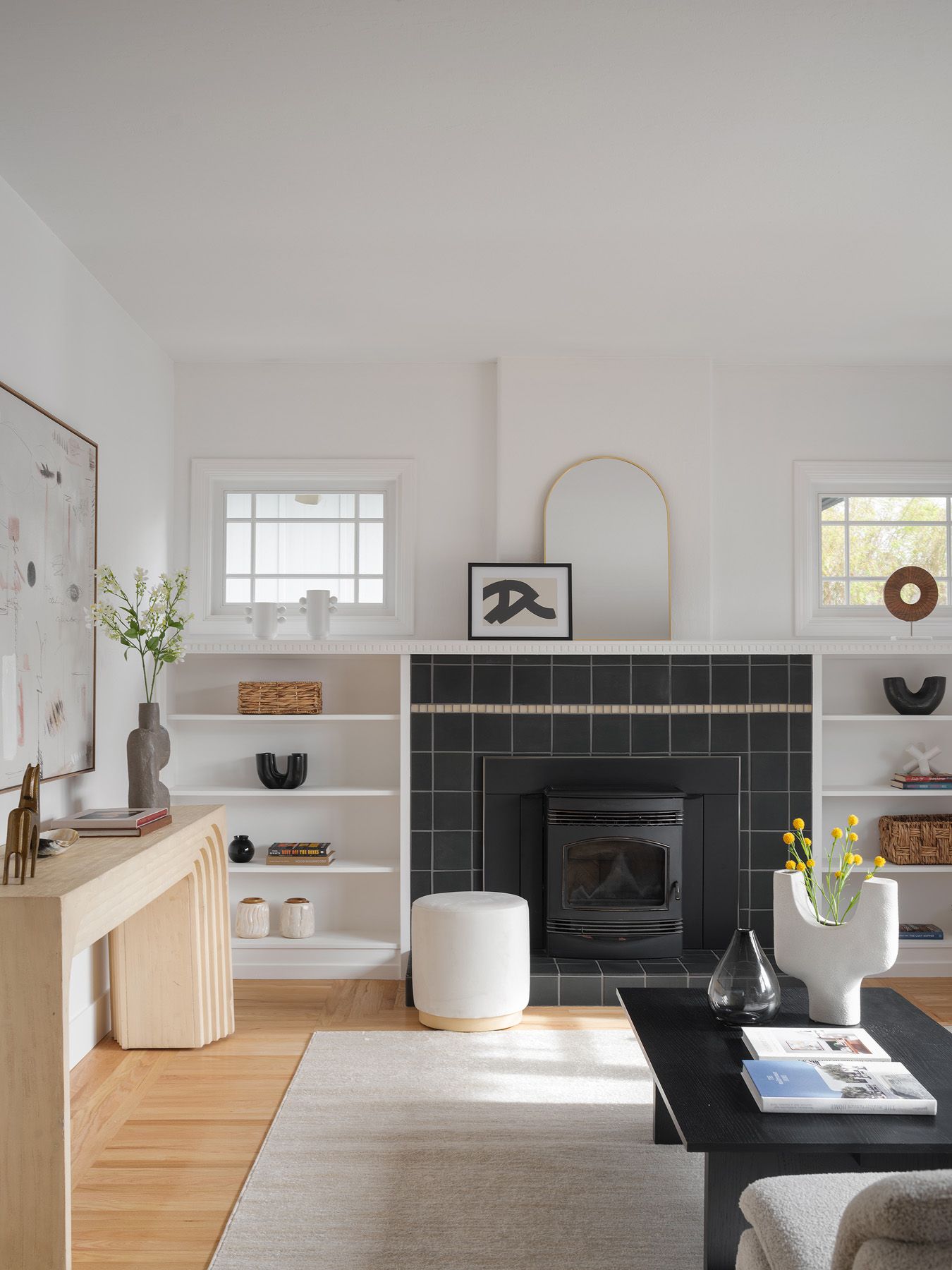 Staged living room with linen sofa, black fireplace, pale wood console, and layered listing-photo depth