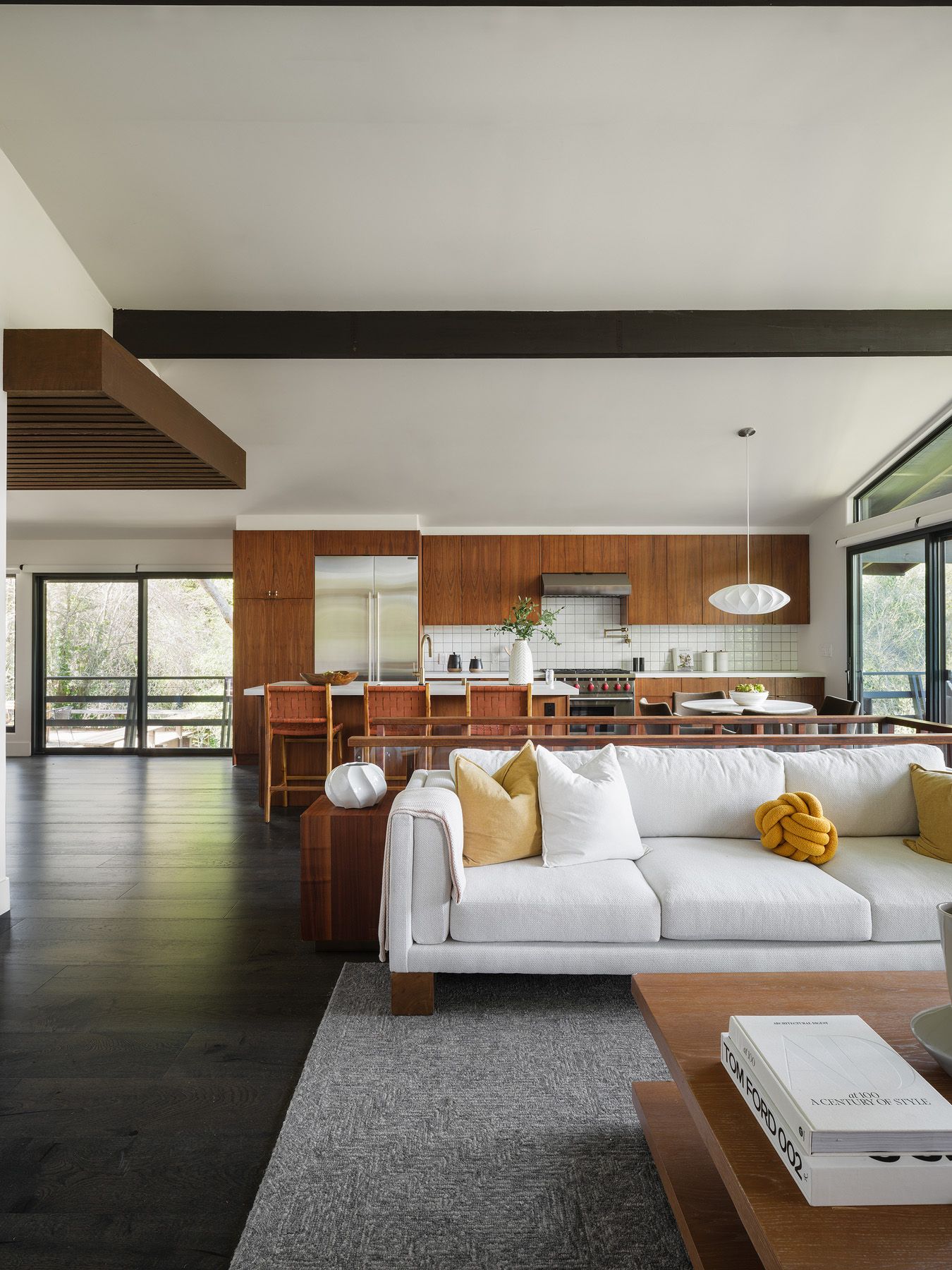 Cream sofa and walnut kitchen cabinetry in an open-plan room, showing how staging makes connected living spaces legible.