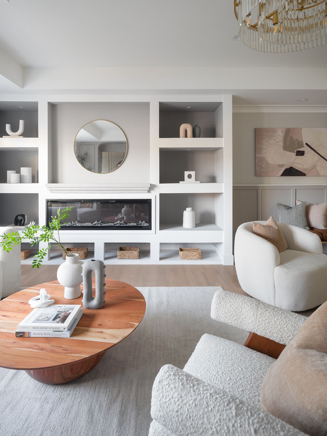 Cream boucle seating surrounds a round wood coffee table beside a built-in fireplace wall, giving the living room a clear focal point.