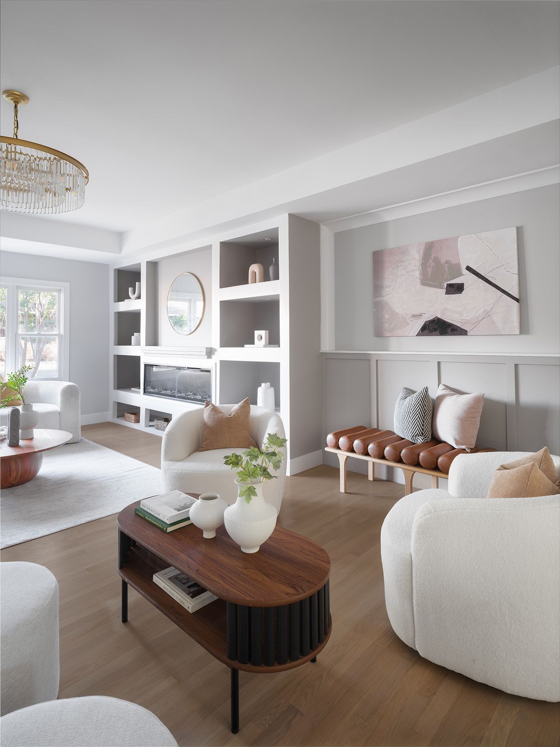 Neutral staged living room with cream bouclé chairs and walnut table supporting perceived value